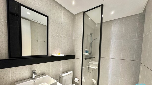 A modern bathroom with a large mirror, a sink, a toilet, and a glass-enclosed shower. - Millerz Square by Mana Mana (Kuala Lumpur)