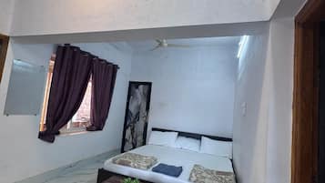 A room with a bed, a table, and a window with curtains.