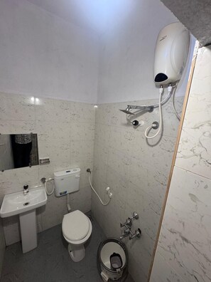 Ein Badezimmer mit Toilette, Waschbecken und einer an der Wand befestigten Handbrause.
