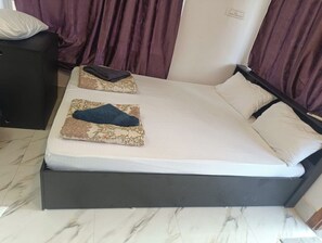 A bed with a dark frame, two pillows, and a blanket. - Silver Sand Beach Homestay (Bhatkal)