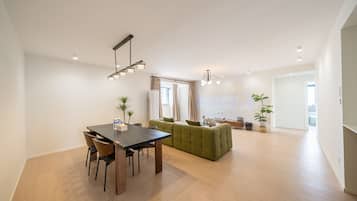 A modern living room with a dining area, a green sofa, and a wooden dining table.