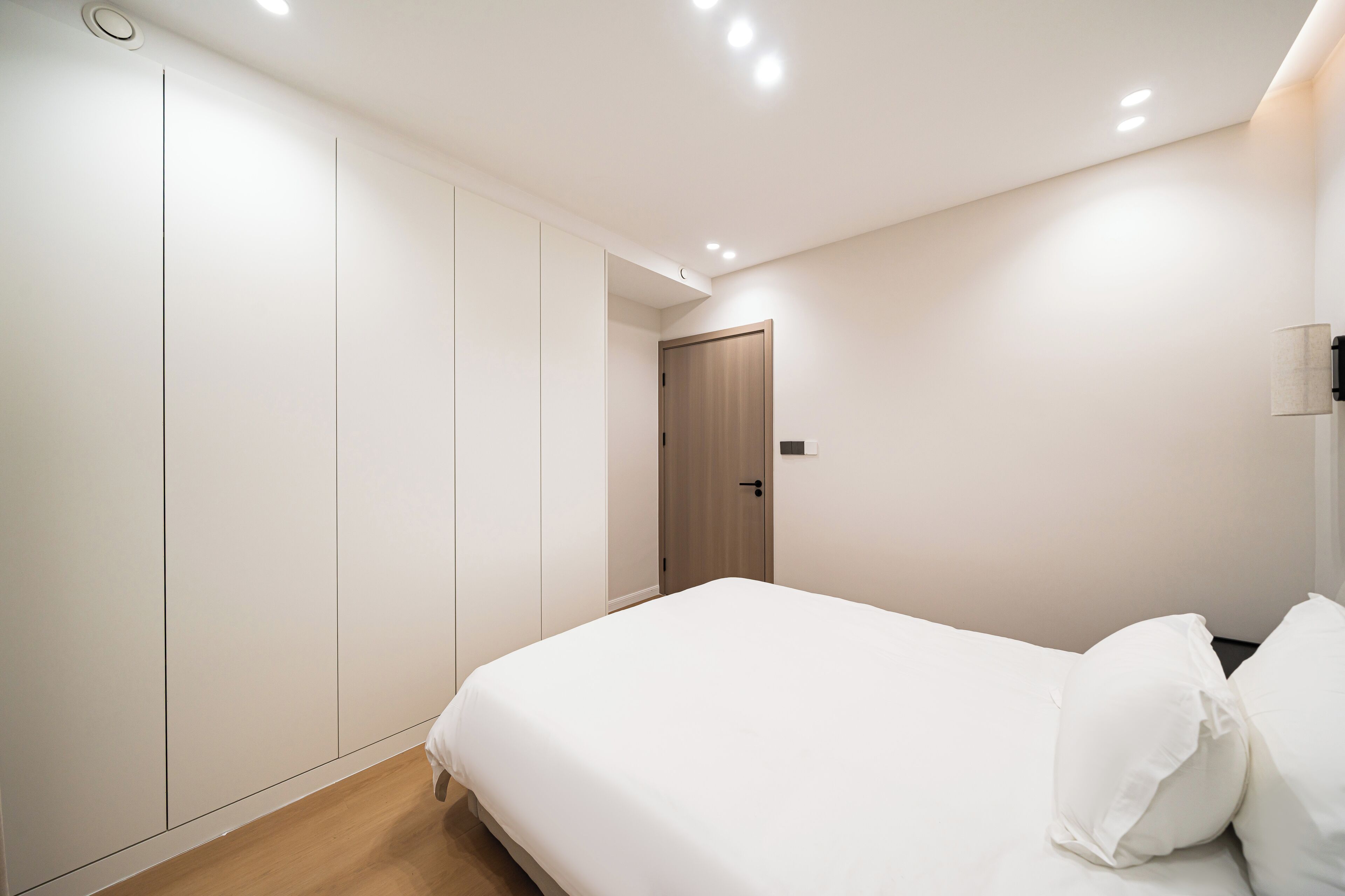 A bedroom with a bed, a wardrobe, and a door.