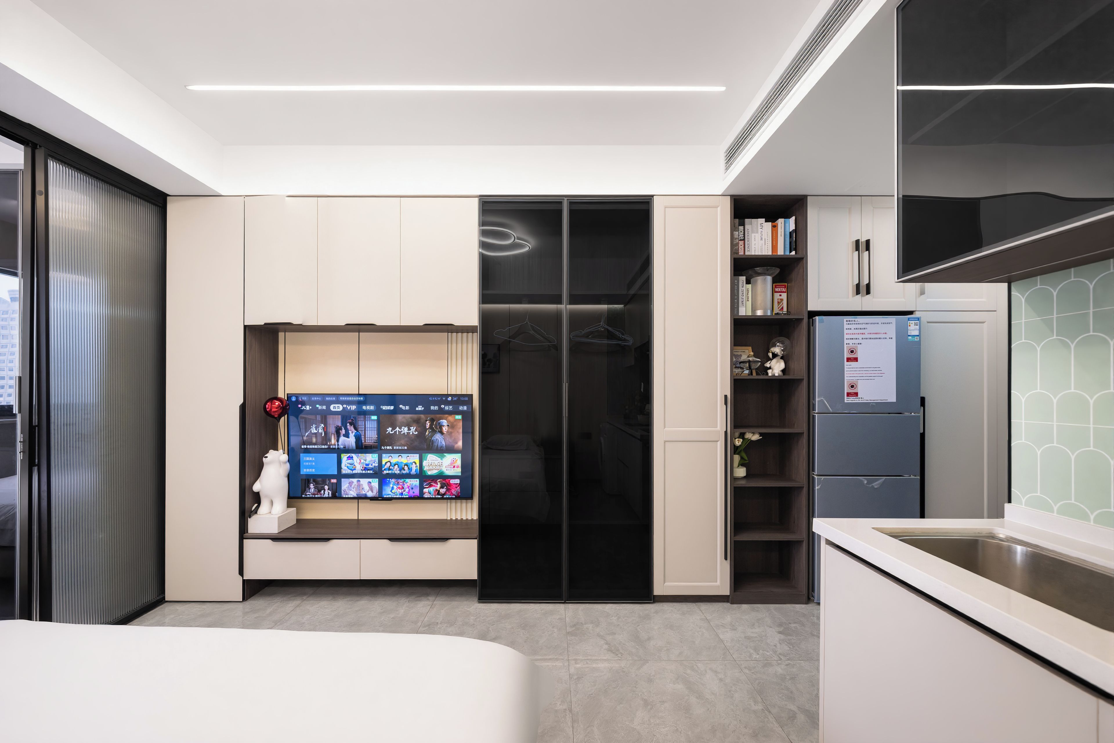 Een moderne slaapkamer met een bed, een aan de muur bevestigde televisie en een inloopkast met schuifdeuren.