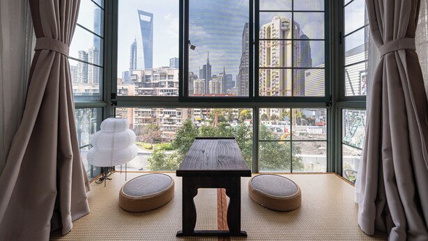 A room with a large window, a table, two cushioned seating areas, and a decorative lamp. - Today Aparthotel (Shanghai)