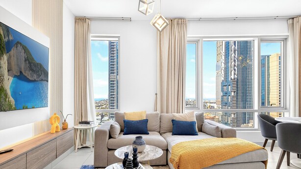 Ein modernes Wohnzimmer mit einer Couch, einem Couchtisch und einem großen Fenster mit Blick auf die Stadt.