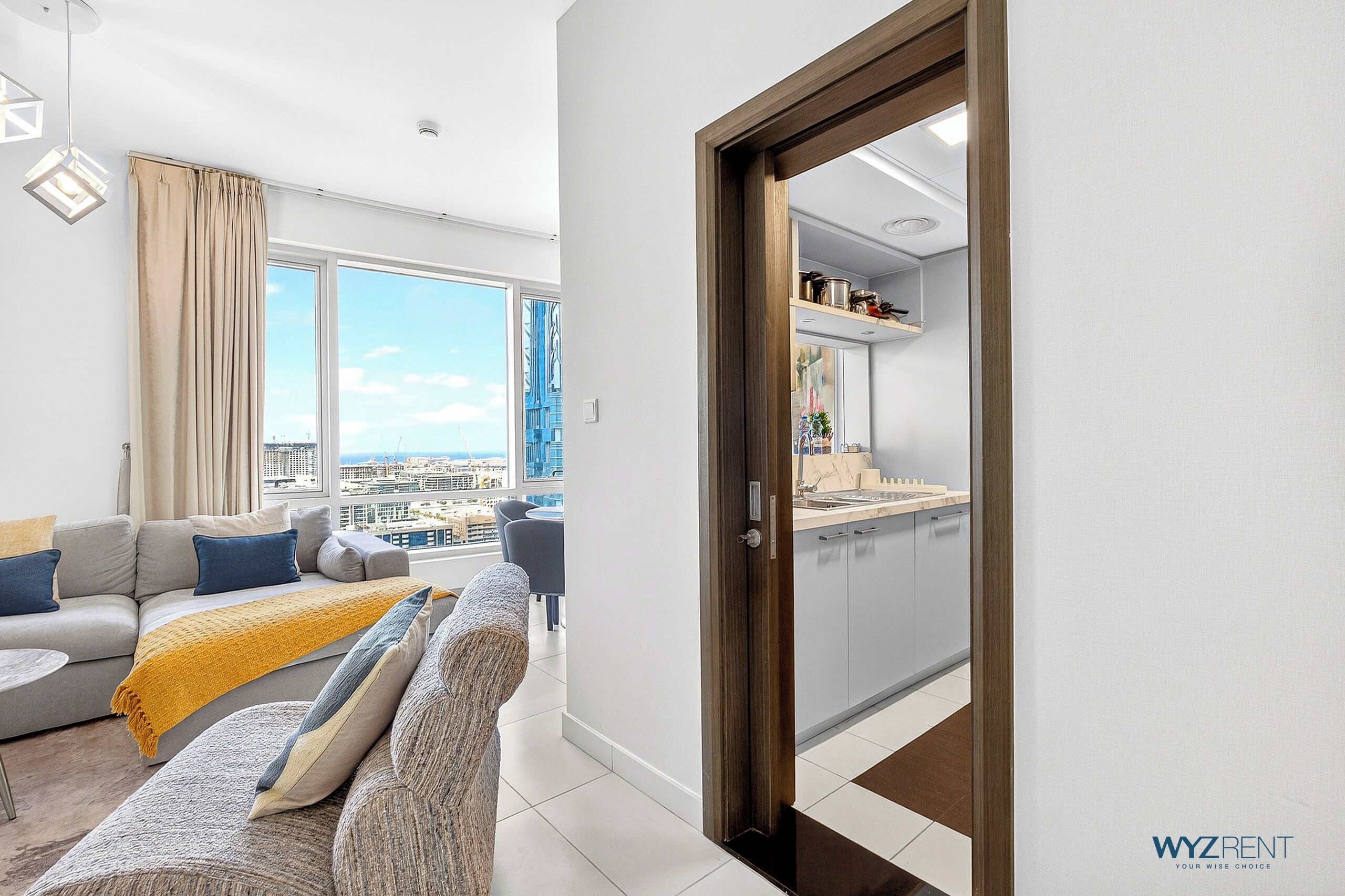A modern living room with a sofa, a yellow throw blanket, and a view of the city through large windows.