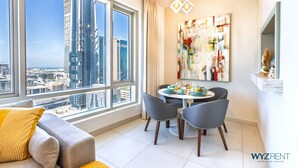 Ein modernes Wohnzimmer mit großem Fenster, Essbereich und Blick auf die Stadt.