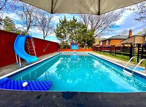 A rectangular swimming pool with a blue slide and a ladder on one side. - Peaceful 1-bedroom house with AC in Richmond Hill (Richmond Hill)