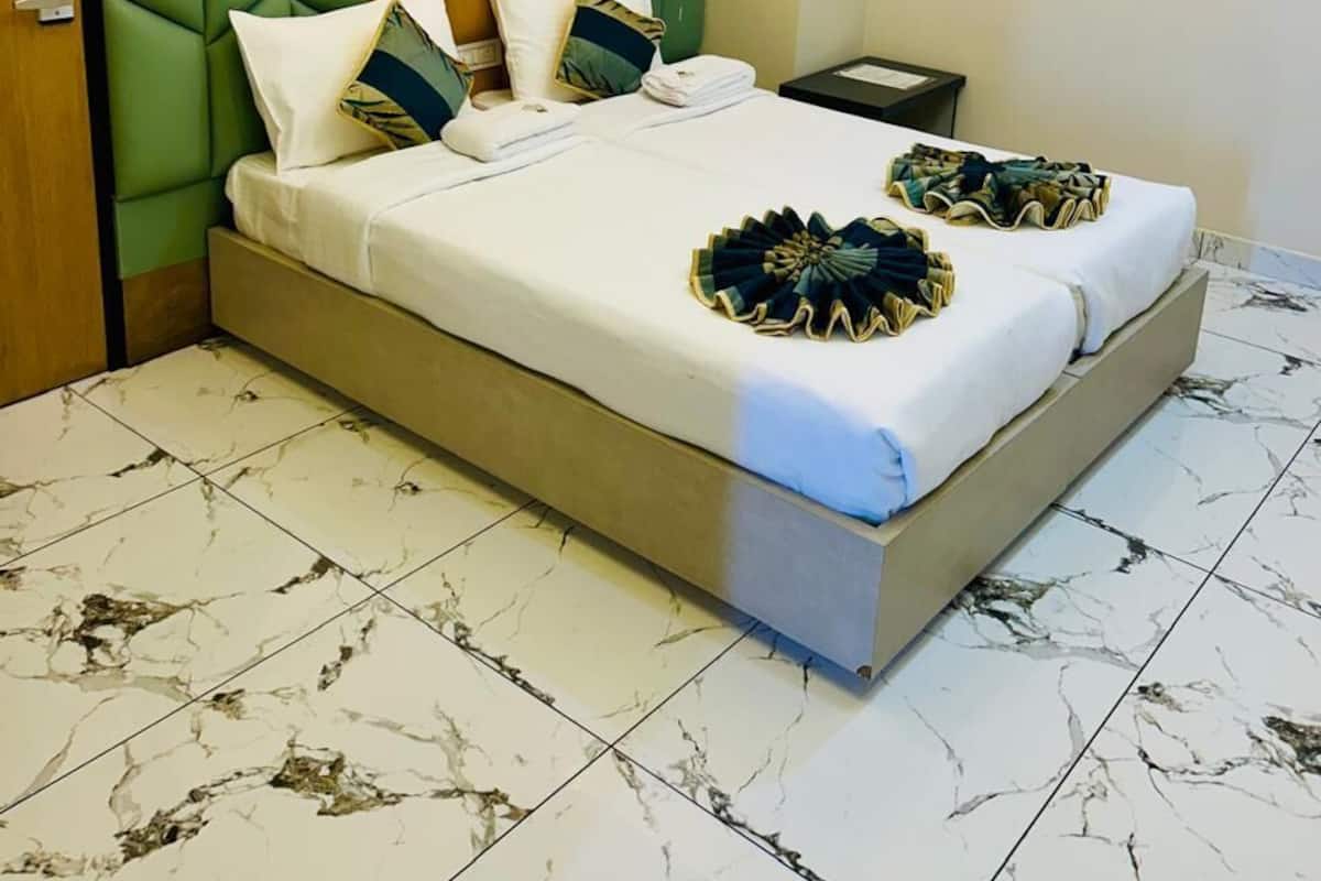 A hotel room with a bed, a nightstand, a wall socket, and a ceiling fan.