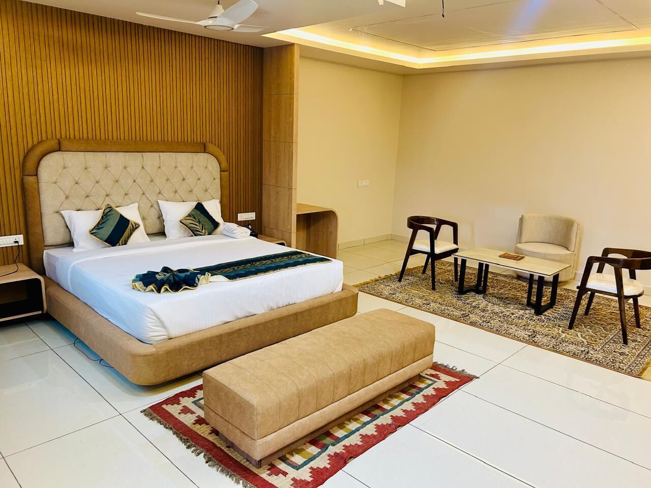 A bedroom with a bed, a sofa, a small table, two chairs, and a rug.