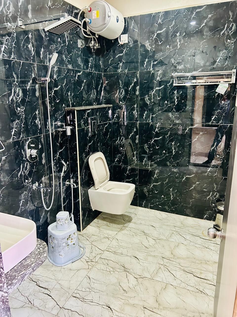 A bathroom with a toilet, shower, and a marble floor.