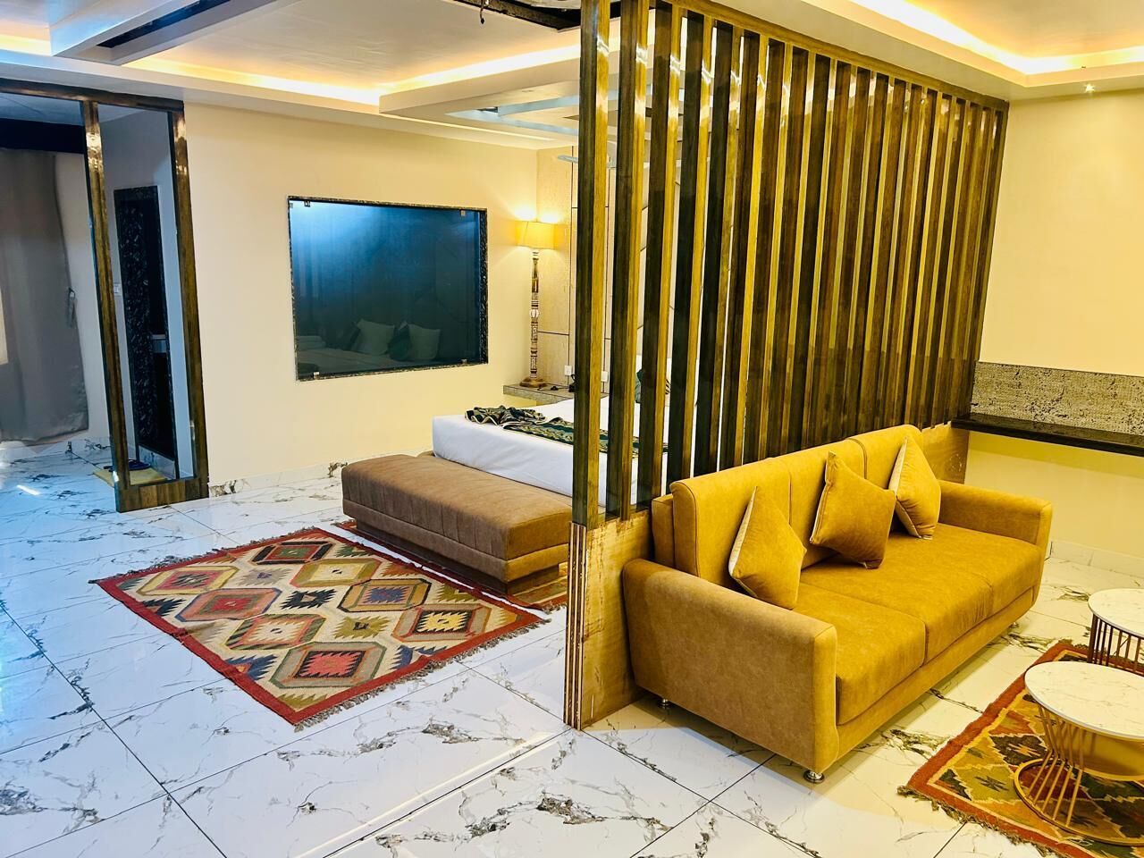 A living room with a sofa, ottoman, and a TV mounted on the wall.