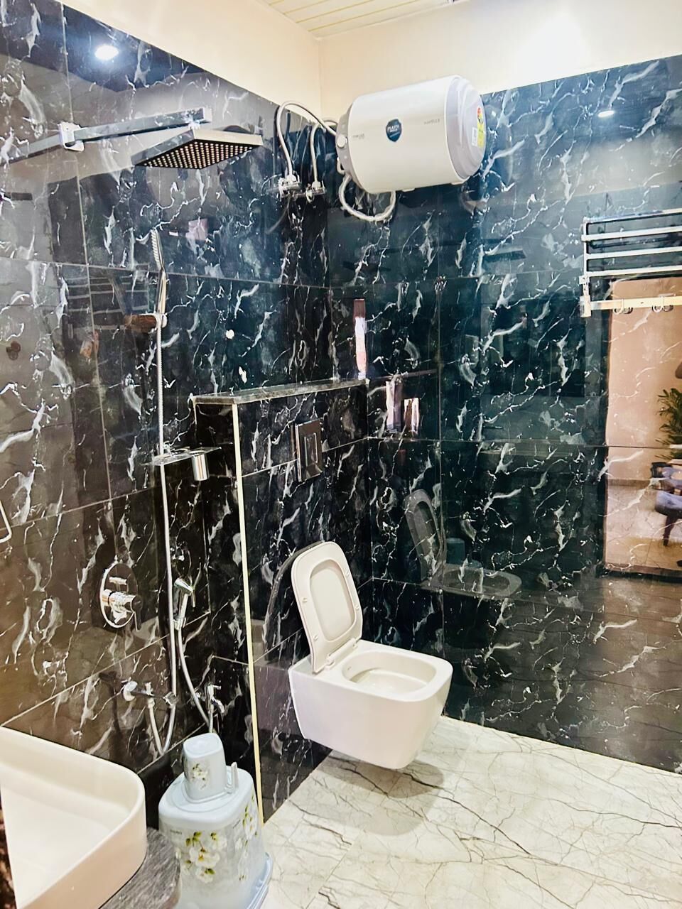 A bathroom with a shower, toilet, and a marble wall.