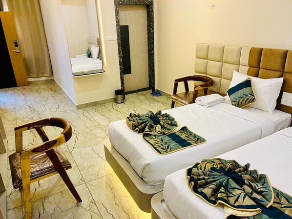 A hotel room with two beds, a wooden chair, a mirror, and a door. - The Hotel Emerald (Nandapur)