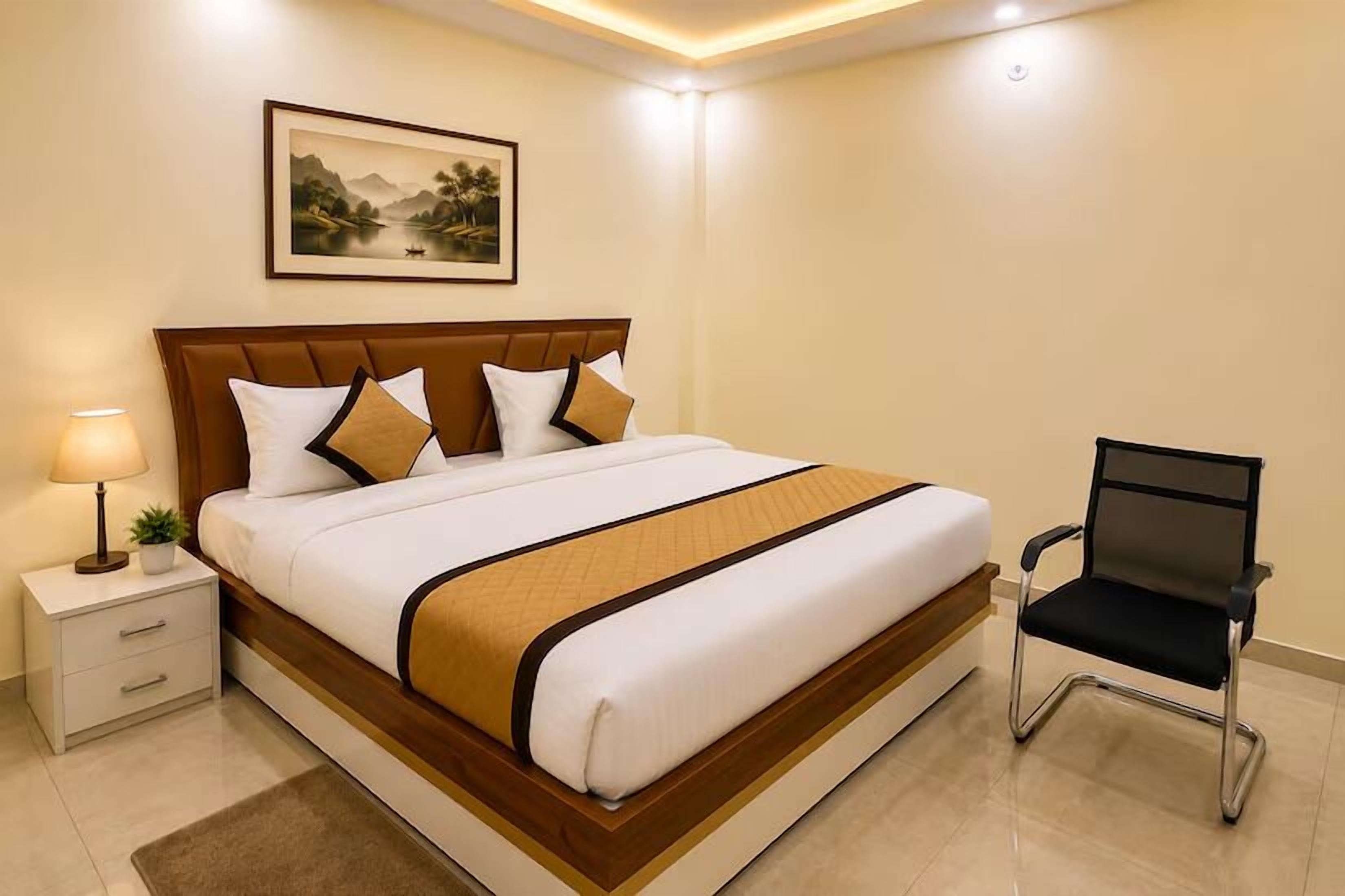 A neatly made bed with a headboard, a bedside table with a lamp, and a chair.