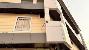 Een modern gebouw met een plat dak, meerdere balkons en een zichtbaar raam met zonwering.
