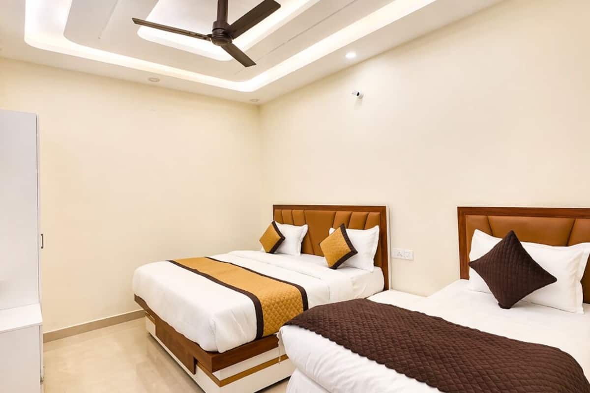 Una habitación de hotel moderna con dos camas, un ventilador de techo, iluminación empotrada y un armario blanco.