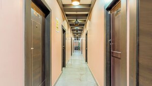 A corridor with doors labeled '101' and '102,' a marble floor, and a ceiling with hanging lights. - Itsy Hotels Relax (Nagaon)