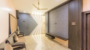A modern hotel lobby with a ceiling fan, a reception desk, a seating area, and a wall-mounted TV. - Itsy Hotels Relax (Nagaon)