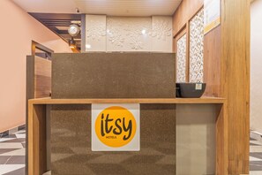 Uma receção com um letreiro 'itsy hotels', um relógio e um painel decorativo.