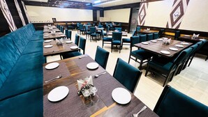 A restaurant with multiple dining tables and booths, arranged in a spacious layout. - Hotel Roop Highlights (Jaipur)