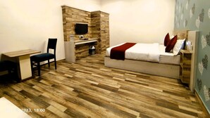 A bedroom with a bed, desk, chair, TV, and ceiling fan. - Hotel Roop Highlights (Jaipur)