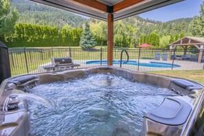 Un jacuzzi con vistas a una piscina y un paisaje montañoso.