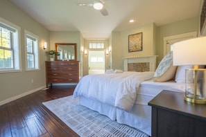 Une chambre à coucher avec un lit, une commode, un miroir et une cheminée.