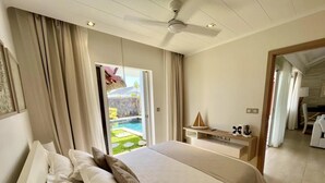 Ein Hotelzimmer mit einem großen Bett, einem Schreibtisch und Blick auf einen Swimmingpool.