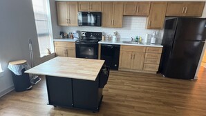 A modern kitchen with wooden cabinets, a black refrigerator, a microwave, and a built-in oven. - 2bed2bath Apartment Located In Downtown Baltimor Area Nice & Cozy (Baltimore)