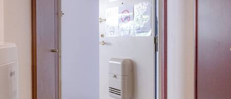 A hallway with a door leading to a room, a hand dryer, and a tiled floor.