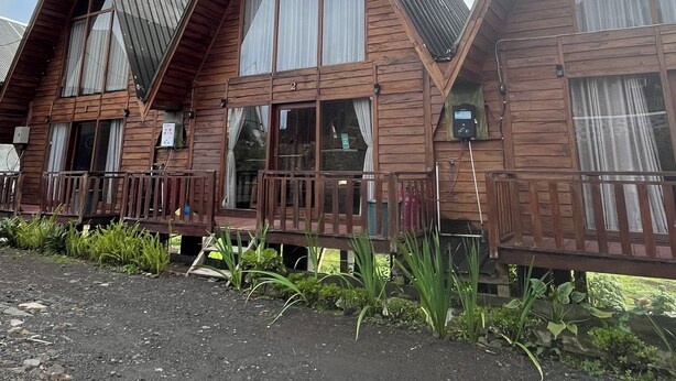 A row of wooden cabins with pitched roofs and large windows, set against a clear sky. - Padangsari Cabin House (Dieng Kulon)