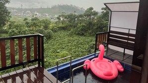 A swimming pool with a pink inflatable float and a view of a green landscape. - Padangsari Cabin House (Dieng Kulon)