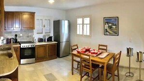 Una cucina moderna con mobili in legno, elettrodomestici in acciaio inossidabile e un'area pranzo con tavolo e sedie in legno.