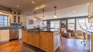 A spacious kitchen with wooden cabinets, a central island, and pendant lighting. - Large Group Retreat Downtown with Hot tub, Fire Pit, Balcony, Office, & More (Durango)