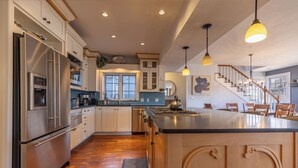 A spacious kitchen with wooden cabinets, stainless steel appliances, and a large island. - Large Group Retreat Downtown with Hot tub, Fire Pit, Balcony, Office, & More (Durango)
