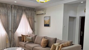 Un salon moderne avec un canapé d’angle, une table basse en marbre et un luminaire contemporain.