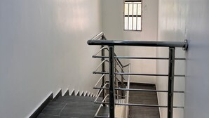 Un escalier avec une rampe métallique, une fenêtre avec des barreaux et un luminaire au plafond.