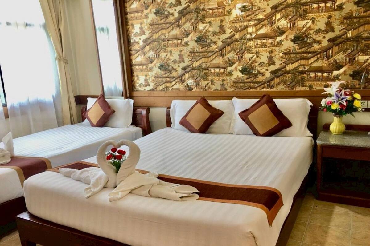 A hotel room with two beds, a large mural, and a bouquet of flowers.