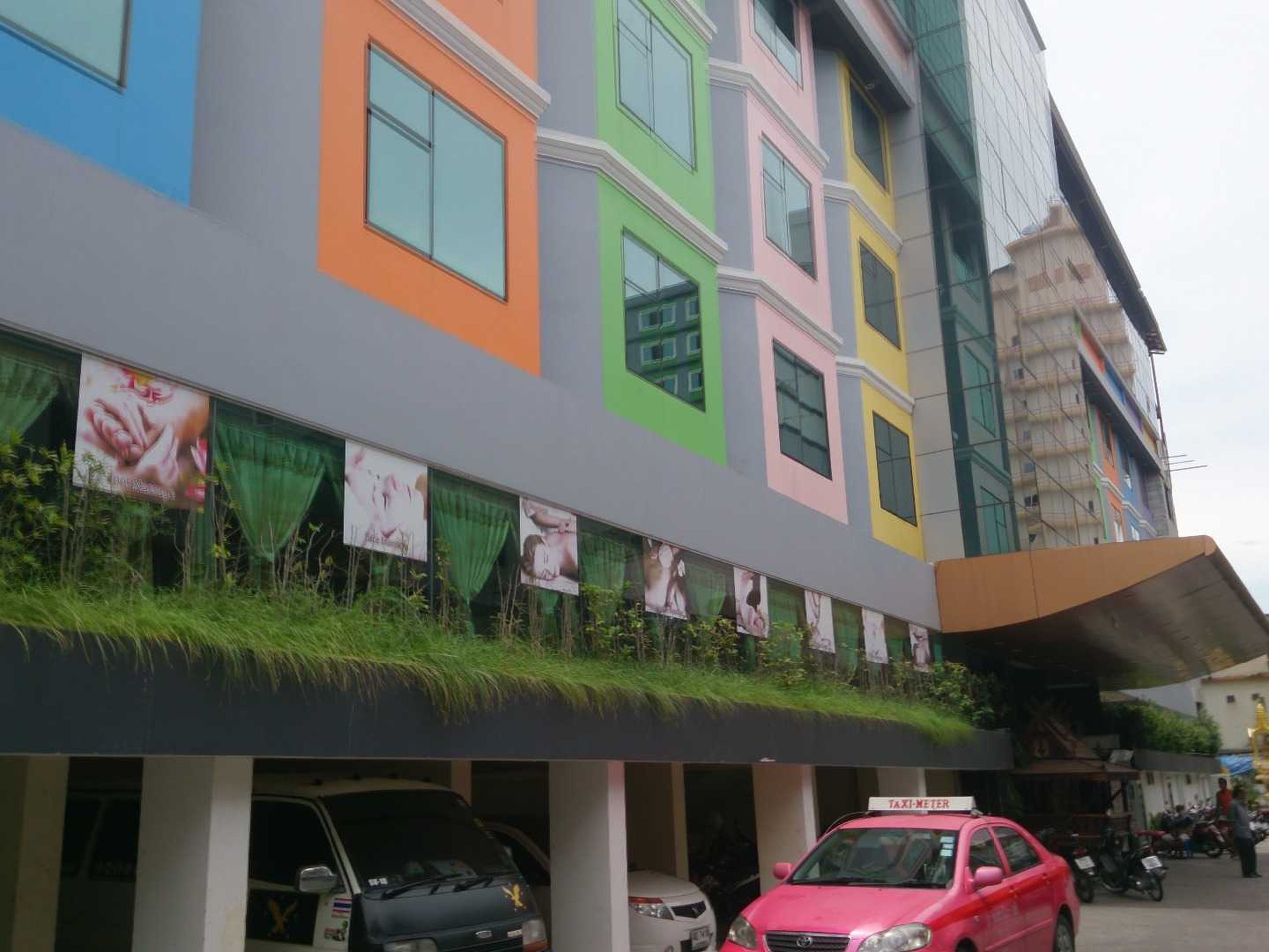 Un edificio a più piani con facciate colorate e una fila di auto parcheggiate davanti.