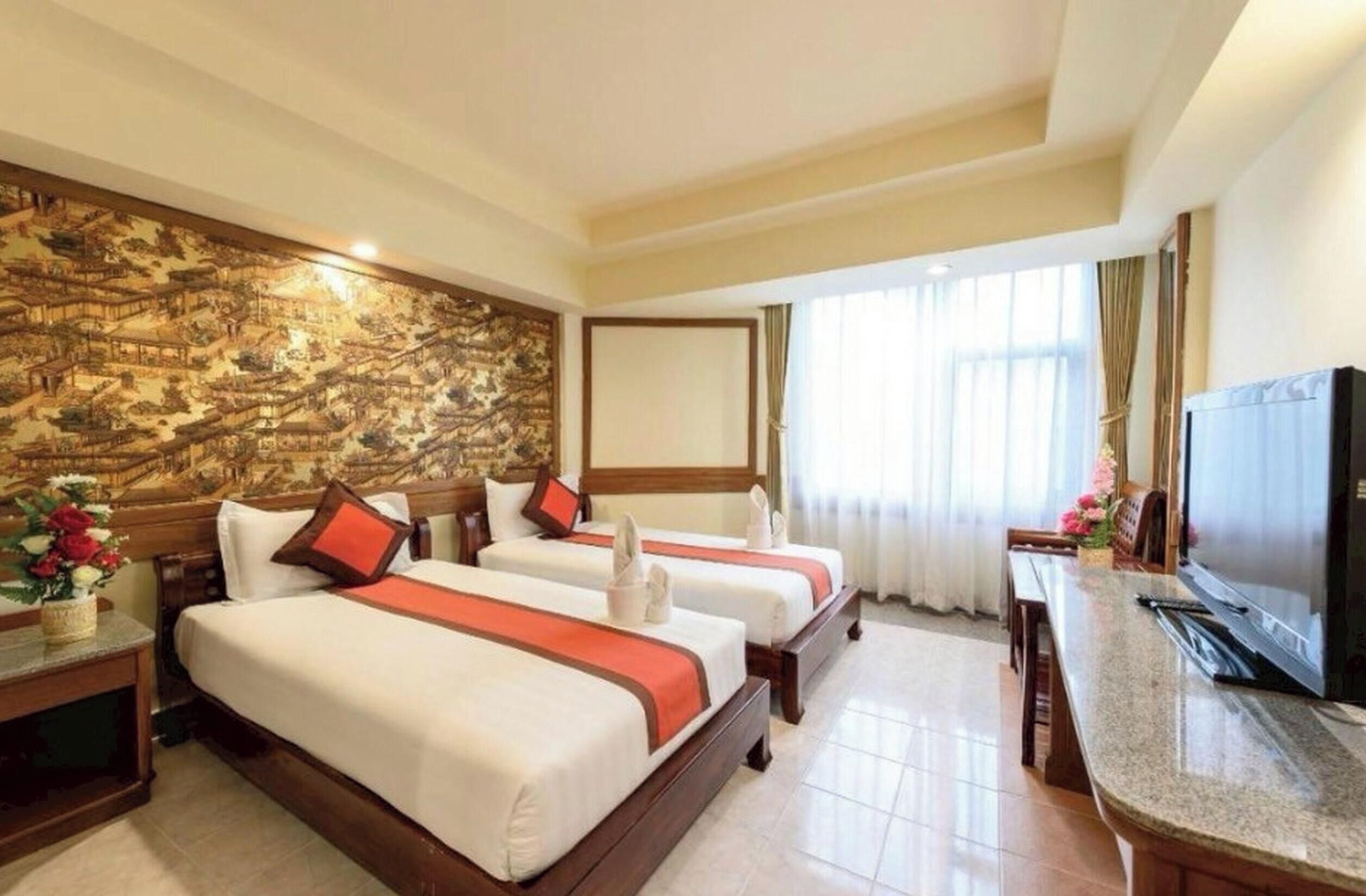 A hotel room with two beds, a television, and a decorative wall.