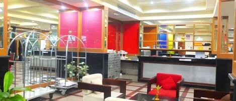 A lobby with a reception desk, seating area, and a large window.