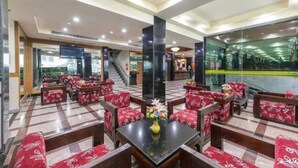 Een hotel lobby met rode gestreepte banken en een centrale tafel met een bloemenvaas.
