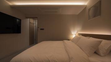 Une chambre d’hôtel avec un lit, un téléviseur fixé au mur et une porte donnant sur une salle de bain.