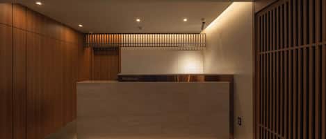 A modern reception area with a wooden reception desk, a reception sign, and a sliding door with vertical slats.