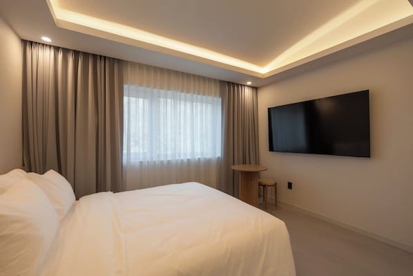 A modern hotel room with a large bed, a flat-screen TV mounted on the wall, and a large window with curtains. - ONSHIMJAE (Pocheon)
