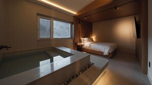 A modern bathroom with a large bathtub, a wooden ceiling, and a bedside table with a lamp. - ONSHIMJAE (Pocheon)