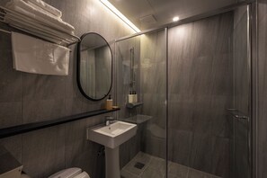 Standaard tweepersoonskamer | Badkamer | Een haardroger, handdoeken, zeep, shampoo
