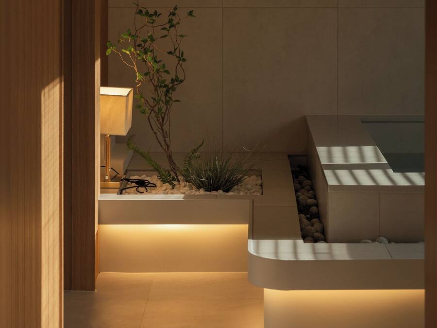 Ein modernes Interieur mit Holztür, beleuchteter Lampe, Pflanze und integriertem Sitzplatz.