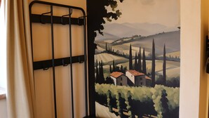 Een kamer met een zwart metalen rek, een zwart-wit geruite vloer en een muurschildering van een landschap.